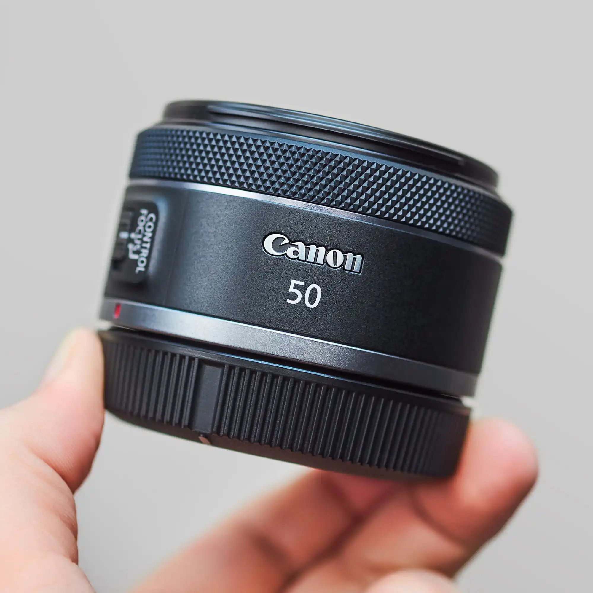نمای نزدیک از لنز Canon RF 50mm f/1.8 STM با نمایش طراحی ساده، مانت فلزی و حلقه کنترل قابل تنظیم برای بررسی کیفیت ساخت و جزئیات ظاهری