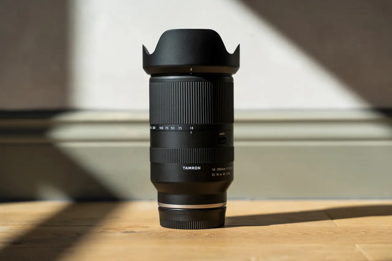 نمای نزدیک لنز Tamron 18-300mm f/3.5-6.3 با طراحی حرفه‌ای، نشان‌دهنده‌ی کیفیت بالای ساخت، سیستم فوکوس VXD و لرزش‌گیر VC. یک لنز همه‌کاره برای عکاسی سفر، پرتره و طبیعت، مناسب برای دوربین‌های Sony E، Fujifilm X، Nikon Z و Canon RF